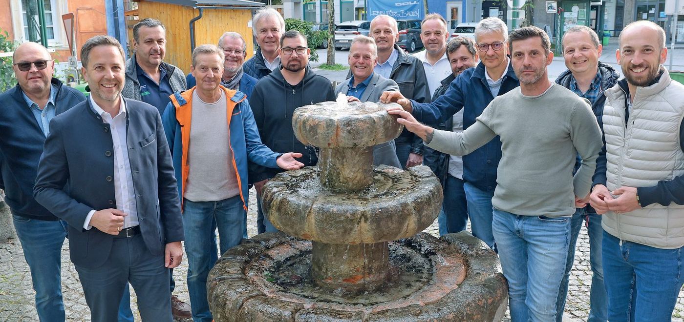Gruppenfoto des Ausschusses der Wassergenossenschaft am Brunnen